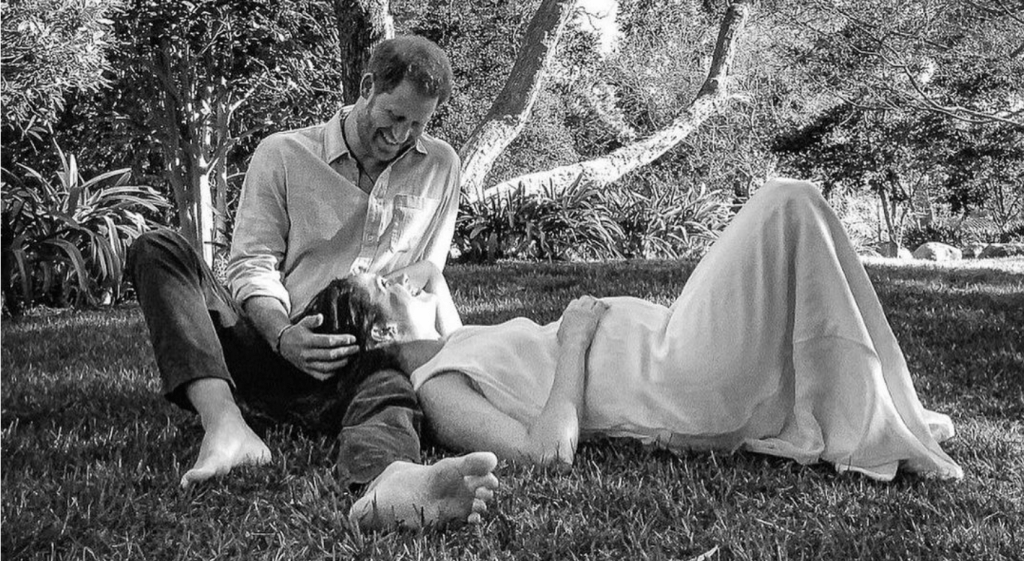 Meghan Markle y el príncipe Harry tumbados en el césped