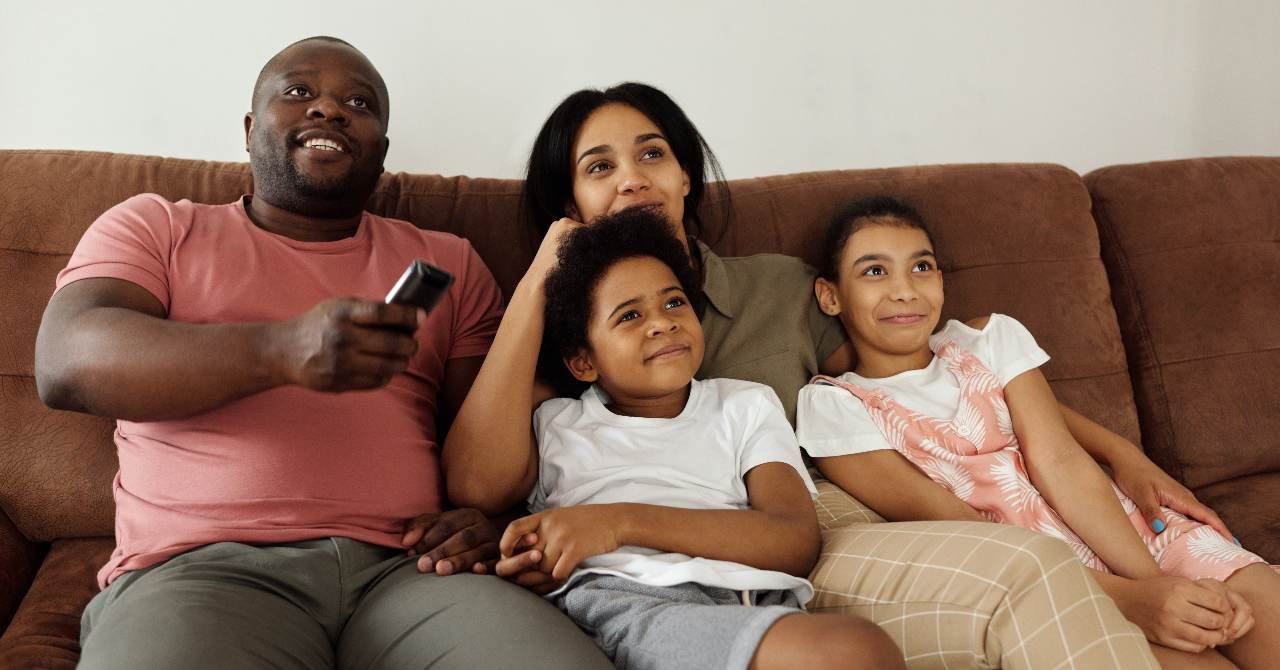 Una pareja y sus dos hijos están sentados en el sofá viendo la televisión el 30 de marzo