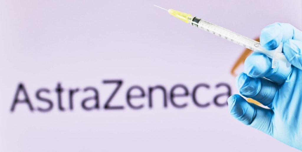 Logotipo de AstraZeneca y mano con una vacuna