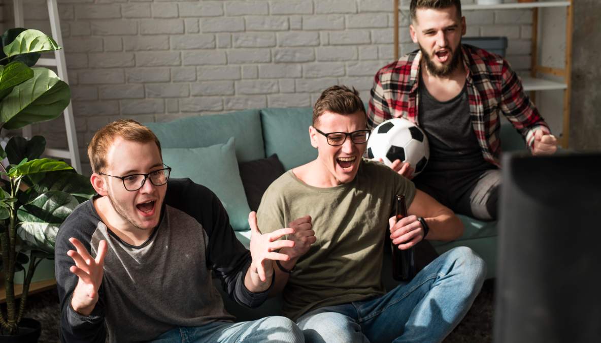 Tres hombres ven un partido de fútbol en la television el 17 de abril