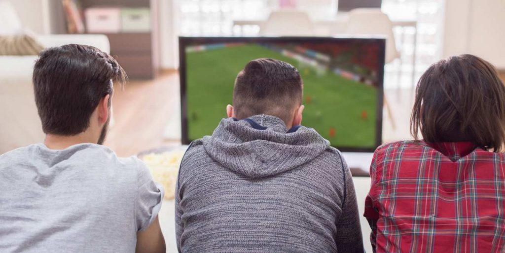 Tres personas viendo un partido de fútbol en la televisión el 3 de abril