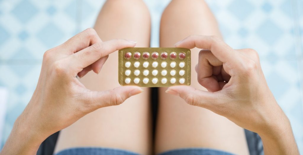 manos de mujer sujetando un paquete de anticonceptivo