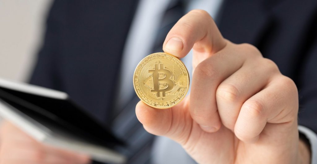Persona agarrando un bitcoin con la mano
